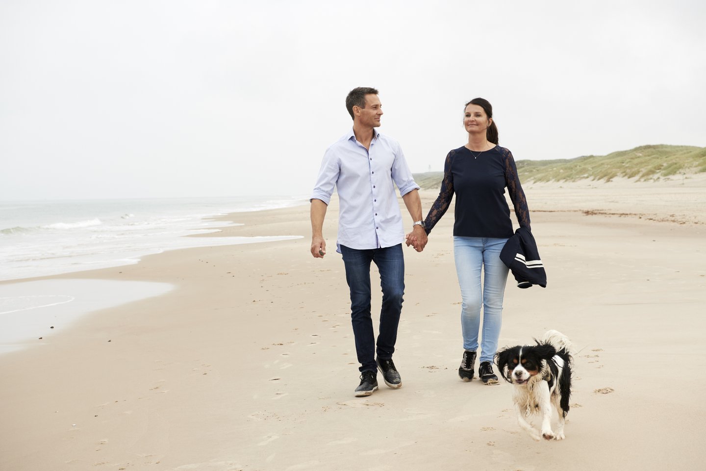 Couple walking with dog on beach in Hirtshals, North Jutland in Denmark