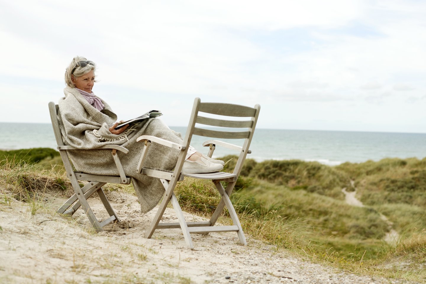 Frau liest in einem Stuhl am Strand in Westjütland an der Dänischen Nordsee