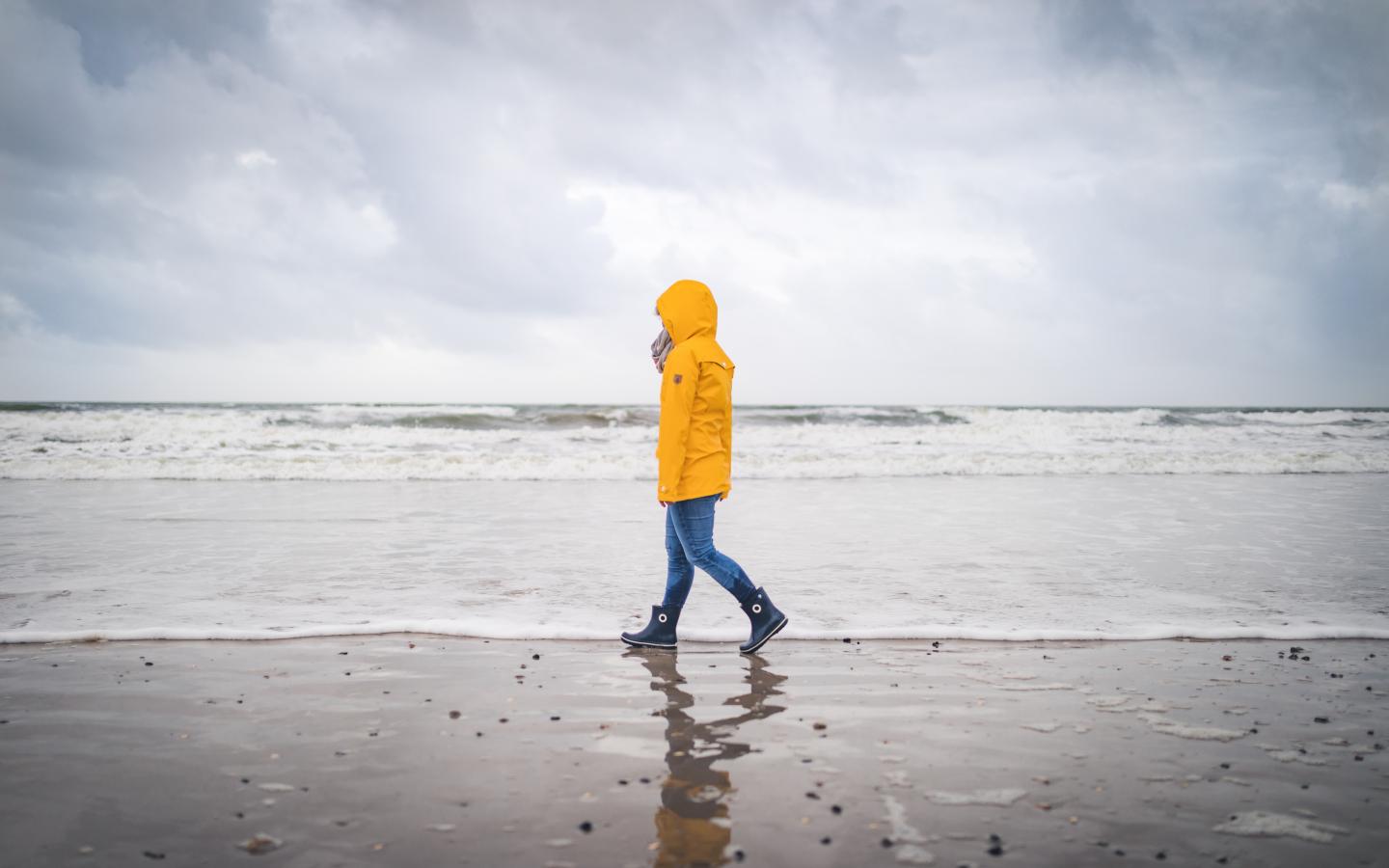 Spaziergänger in gelber Regenjacke am Strand von Blåvand an der Dänischen Nordsee