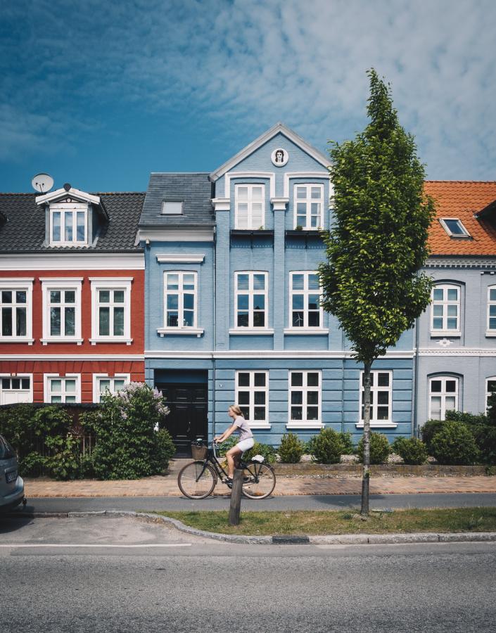 Woman biking in front of colourful houses in Odense, Fyn