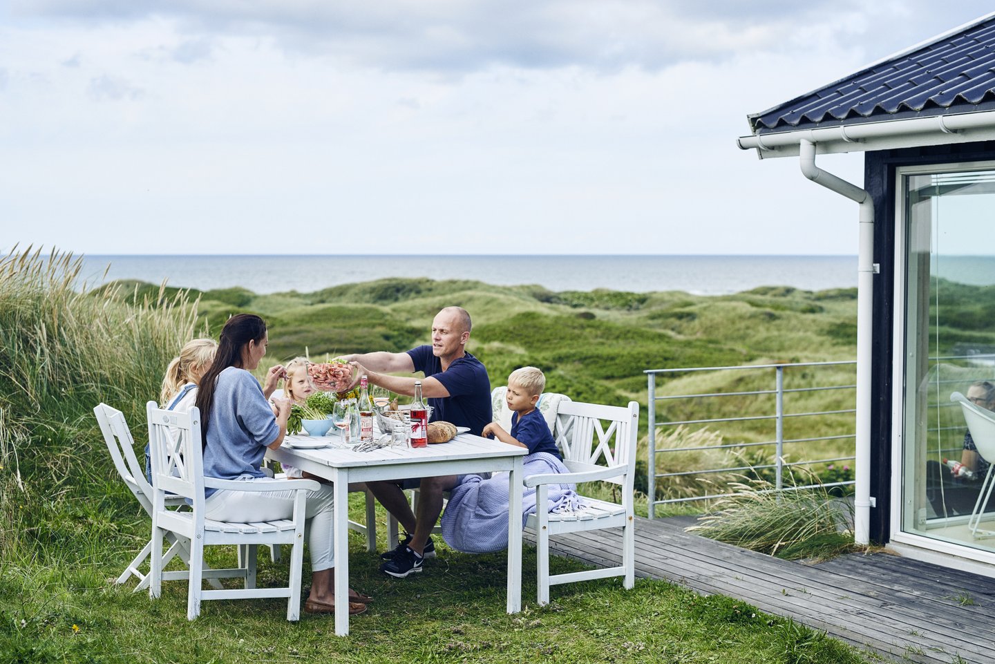 Familie spiser mat utenfor feriehus i Hirtshals