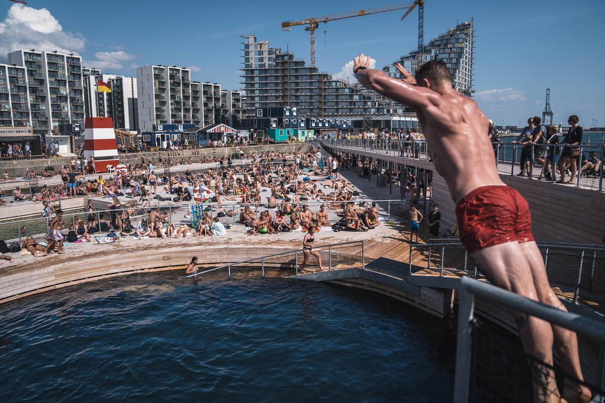 A man dives into Aarhus Harbour Bath, an open air saltwater swimming pool in Denmark, on a sunny day