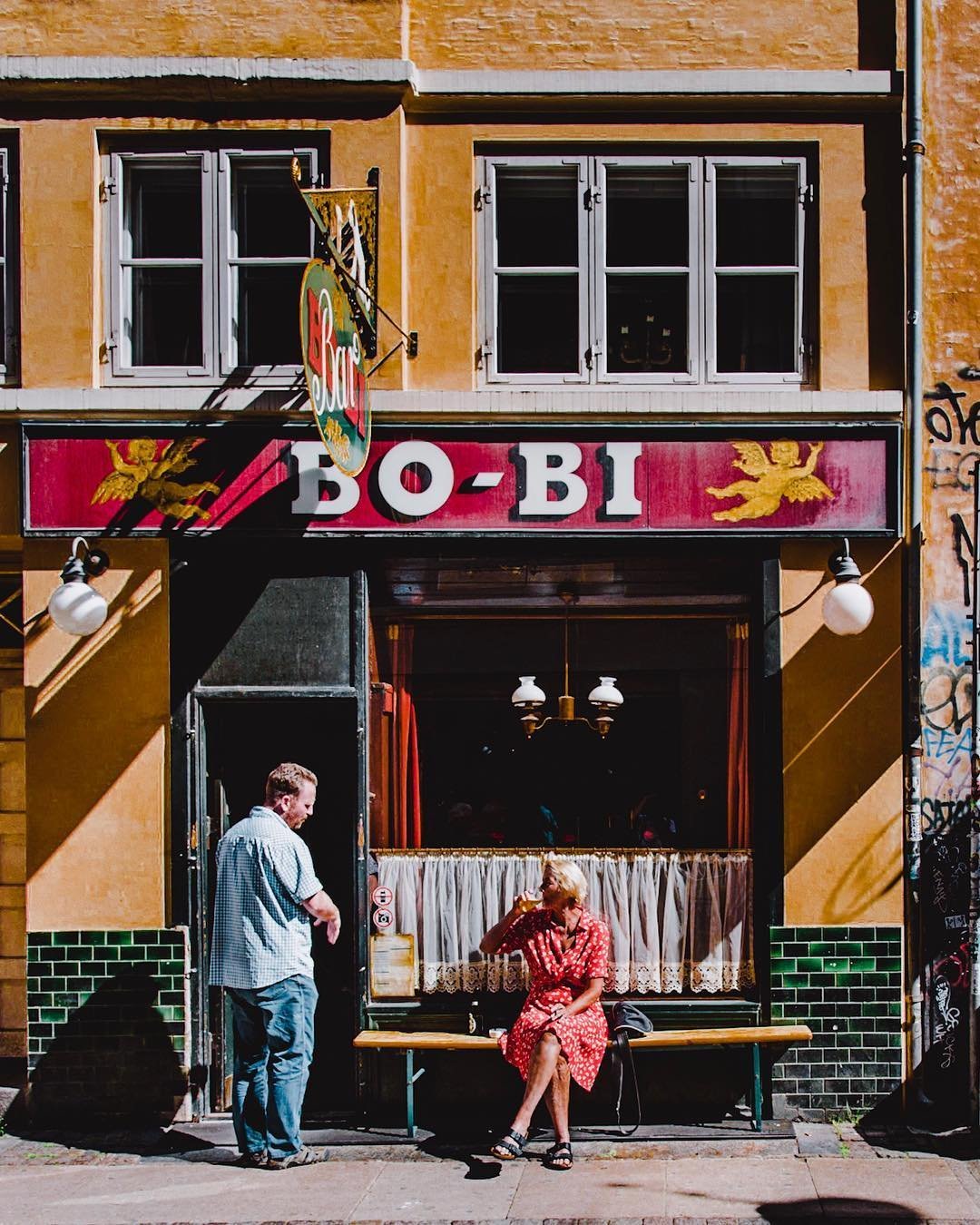 A couple chat outside the bodega Bo Bi in Copenhagen, Denmark - a Danish version of a local pub