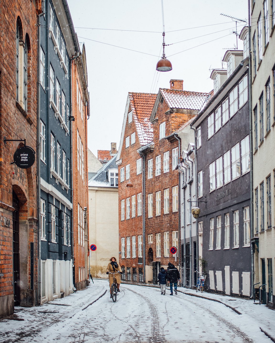 A woman cycles down snowy Magstræde in Copenhagen, Denmark