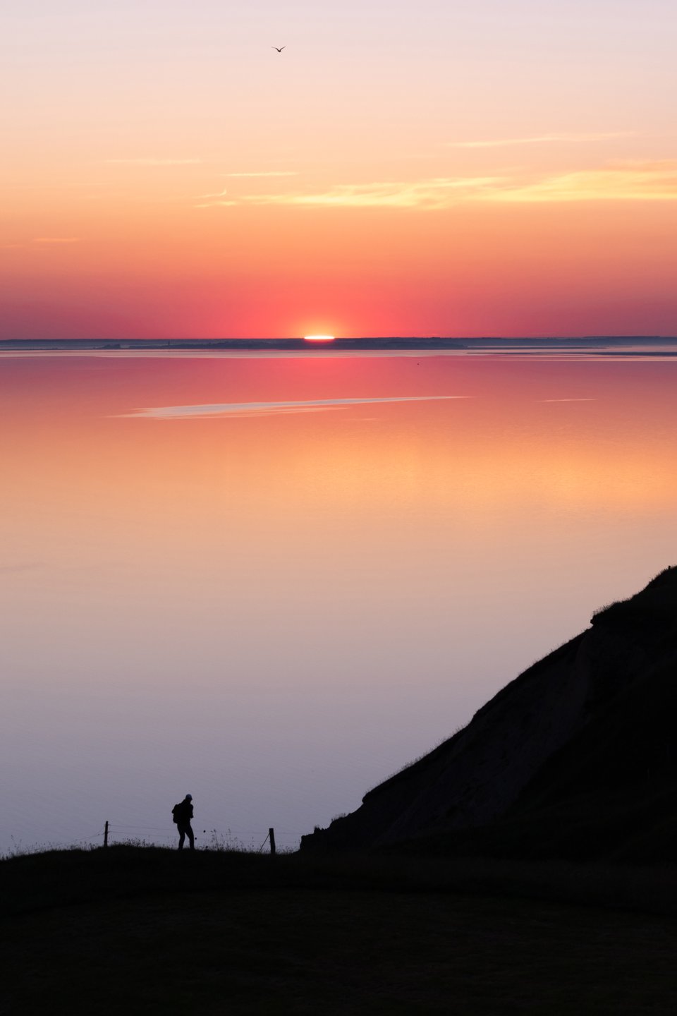 A hiker enjoying the view and sunset over Limfjorden from Hanklit on Mors.