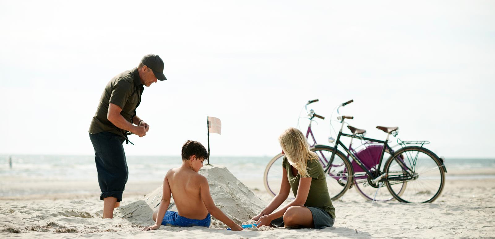 Famile am Strand mit ihren Fahrrädern, Dänemark