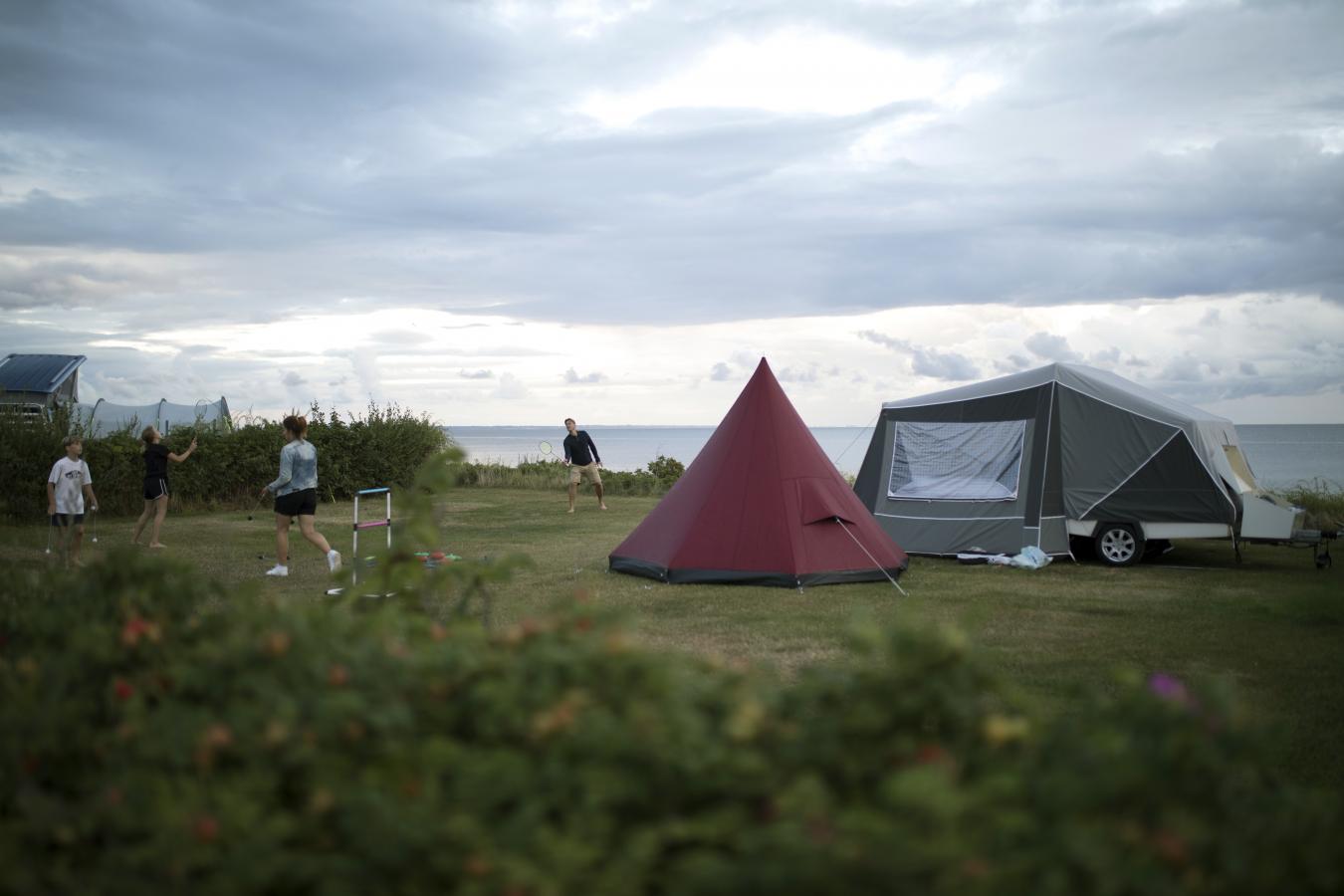Familie spielt vor einem Camping-Zelt am Strand in Dänemark