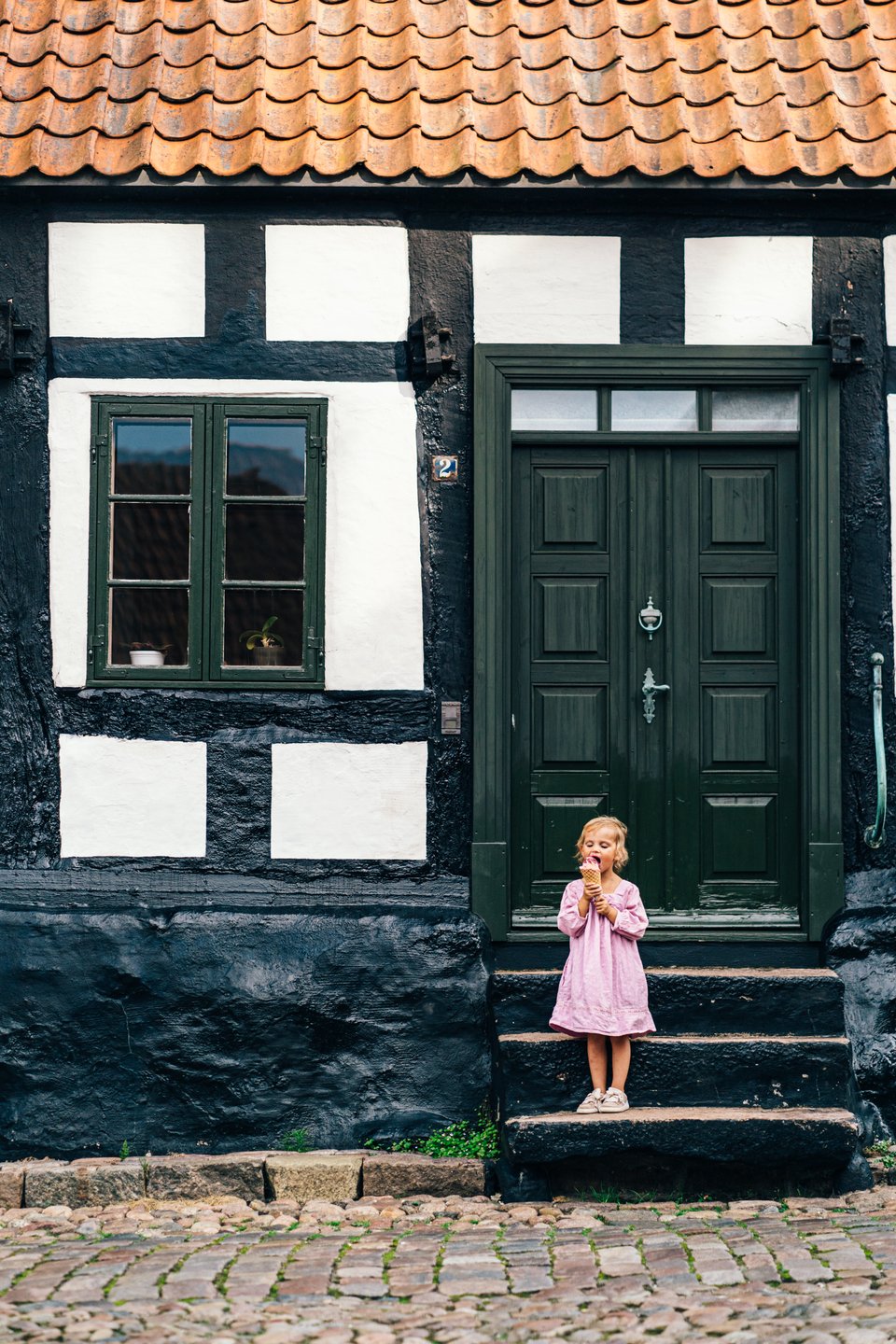 A little child eats ice cream on the stairs in front of a house, Ebeltoft