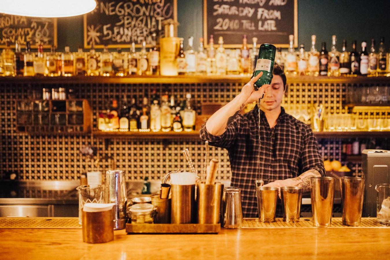 bartender mikser cocktails ved baren Lidkoeb i København, Danmark