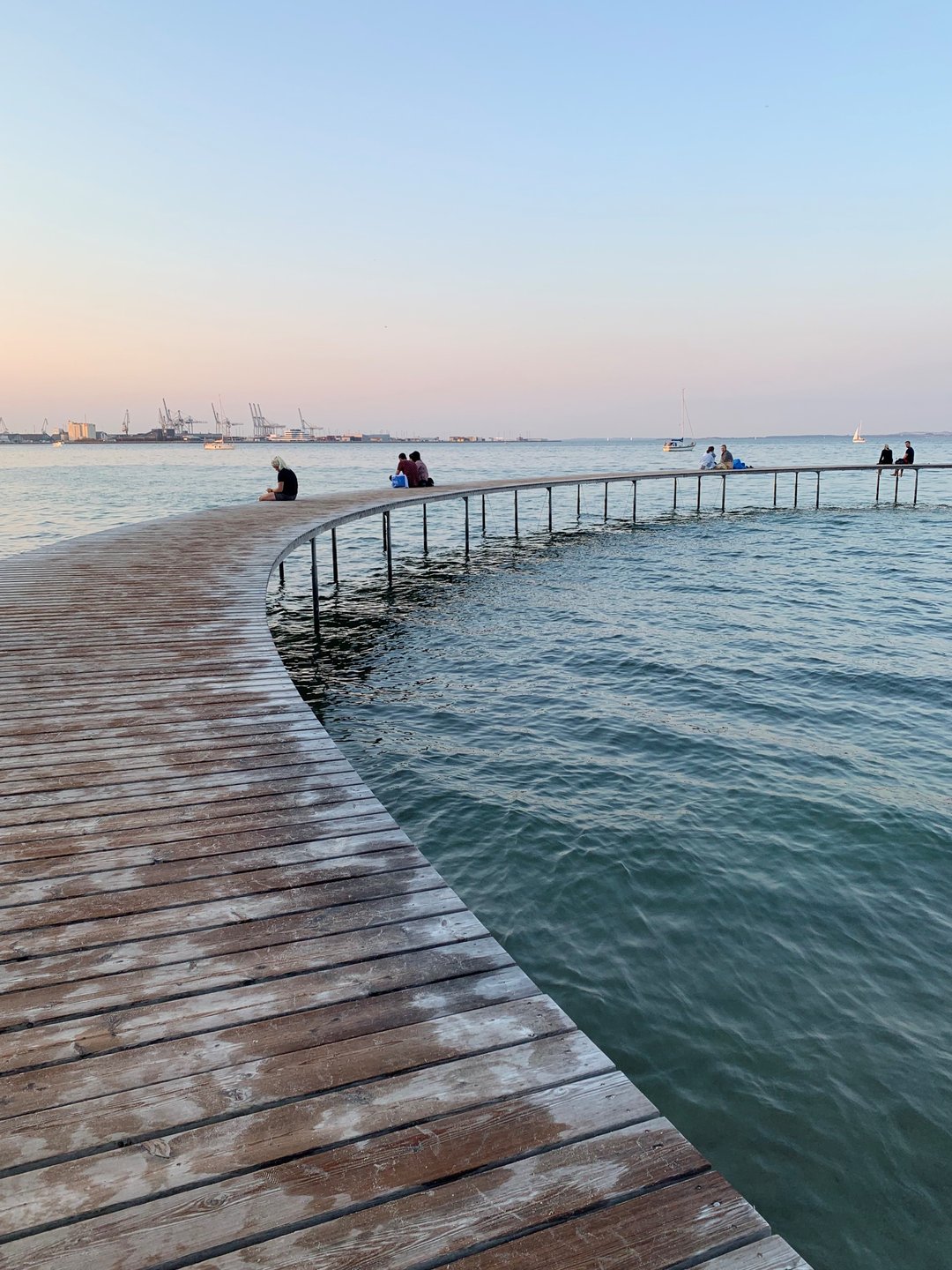 People sitting on the Infinete Bridge at dusk in Aarhus