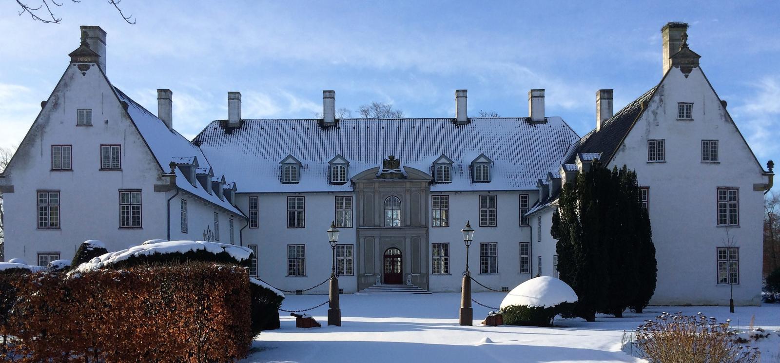 Bild vom Schloss Schackenborg in der Winterzeit, das von Schnee bedeckt ist. 