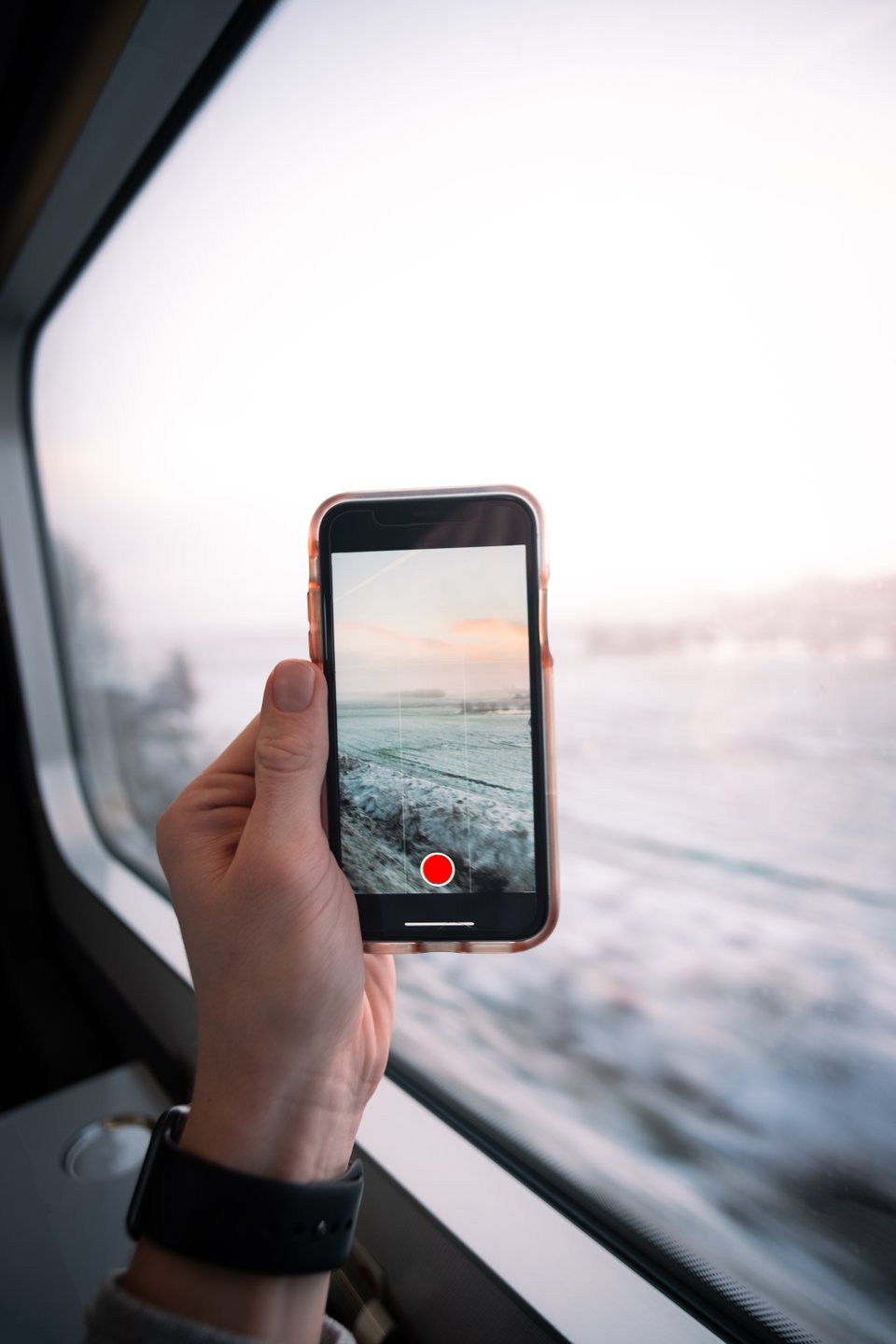 Hand holding a phone taking a photo in train near Aarhus