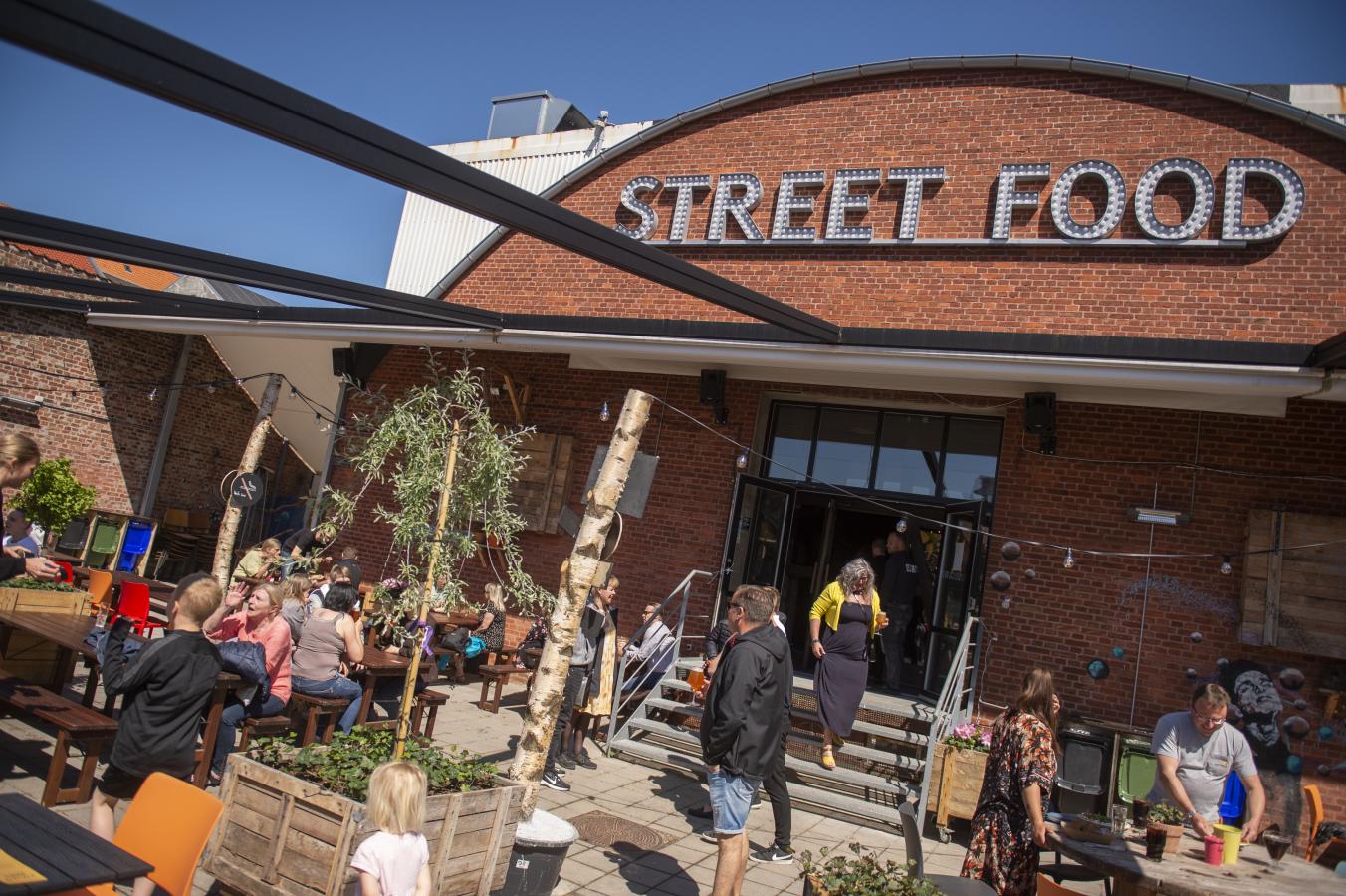 Mennesker nyter solen og mat på uteservering ved Esbjerg Street Food