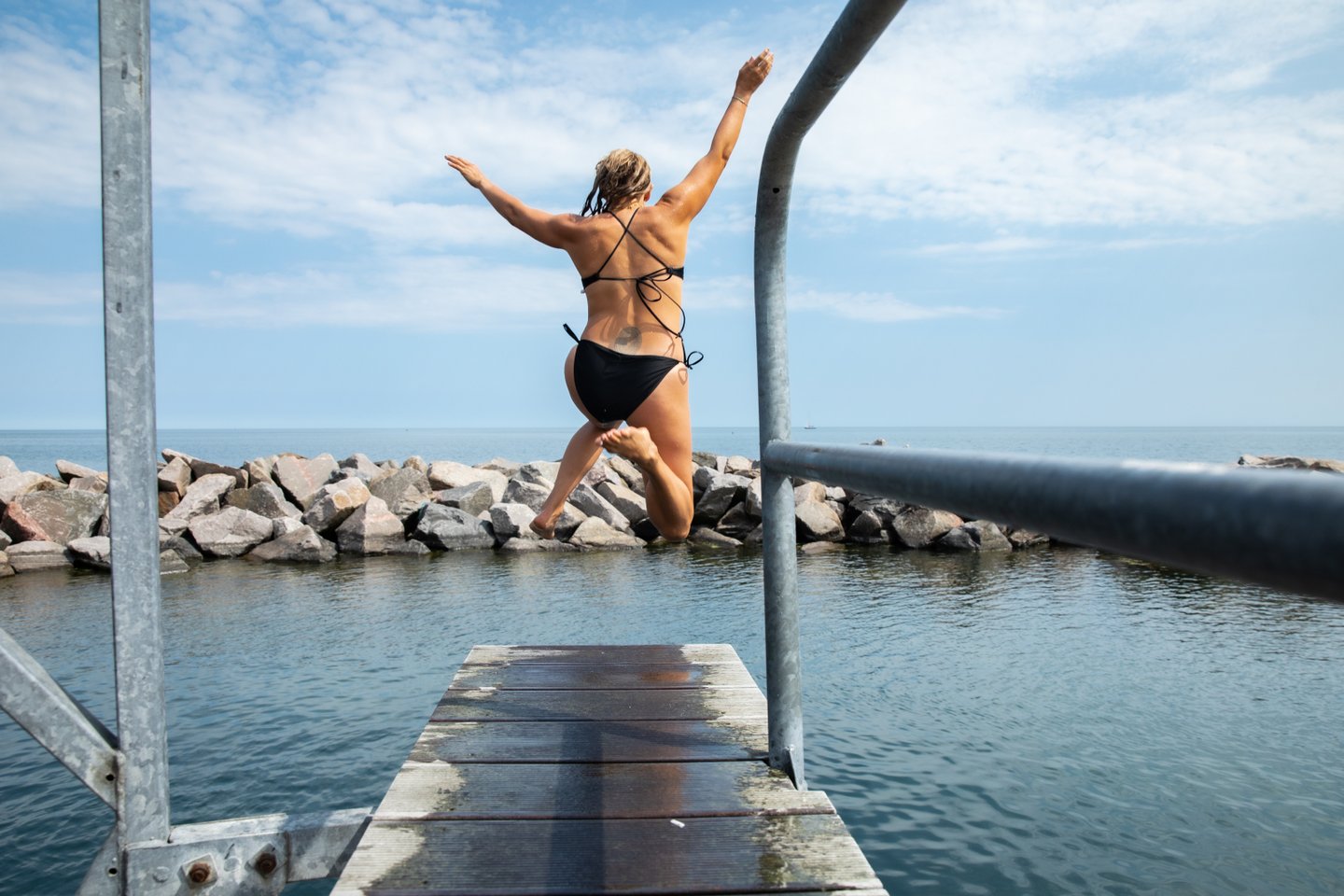 Person jumping in water at Svaneke harbour in Bornholm