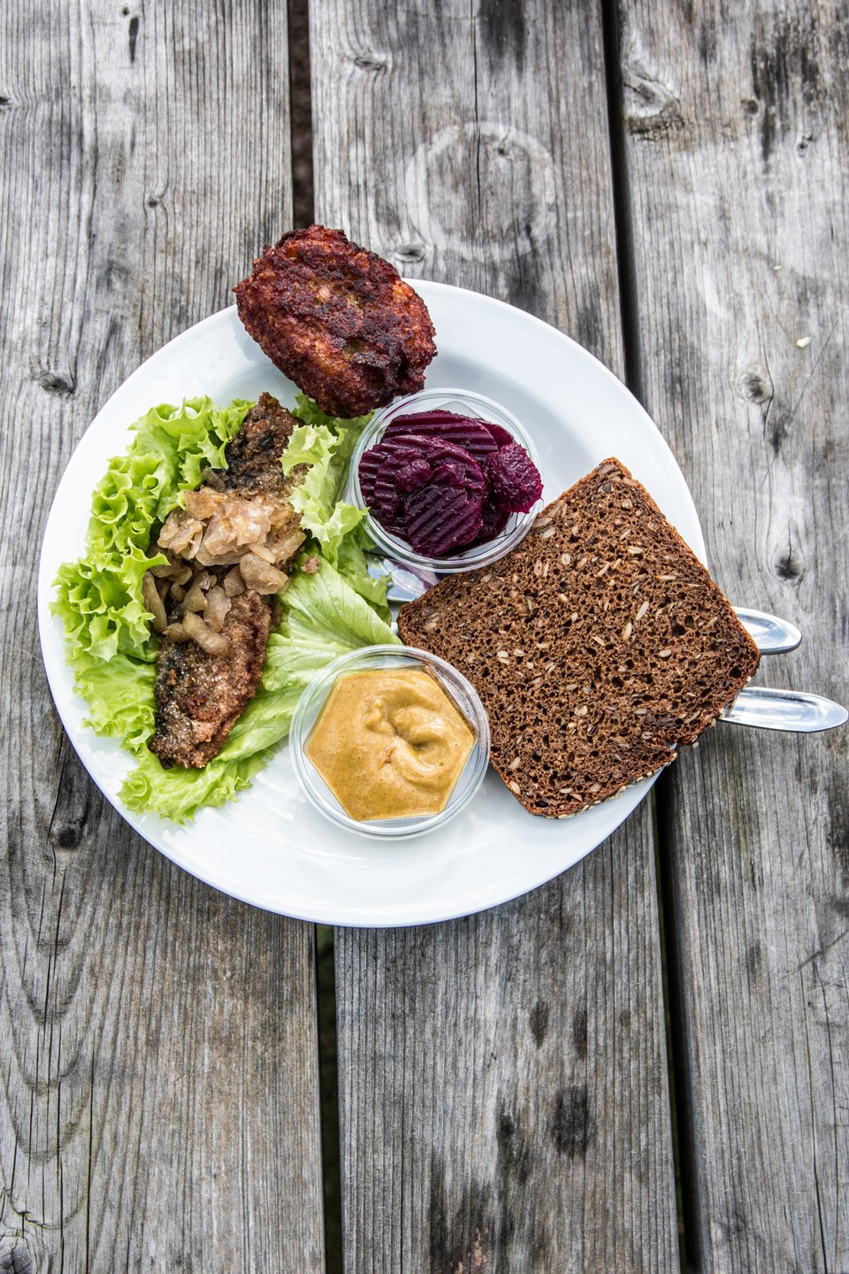 Tallerken med klassisk dansk smørrebrød med sild og frikadelle på et bord