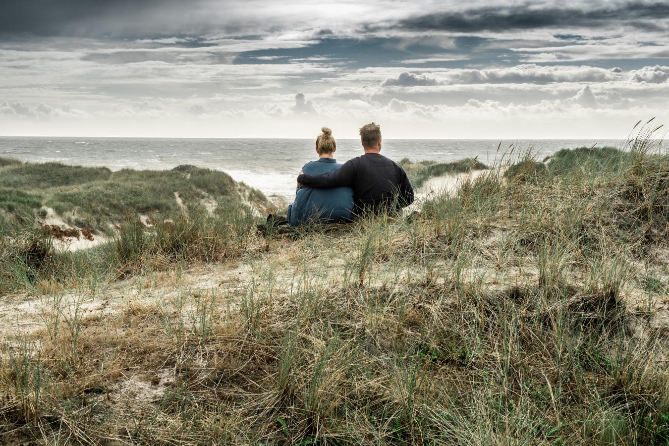 Couple sitting in dunes at West coast, West Jutland