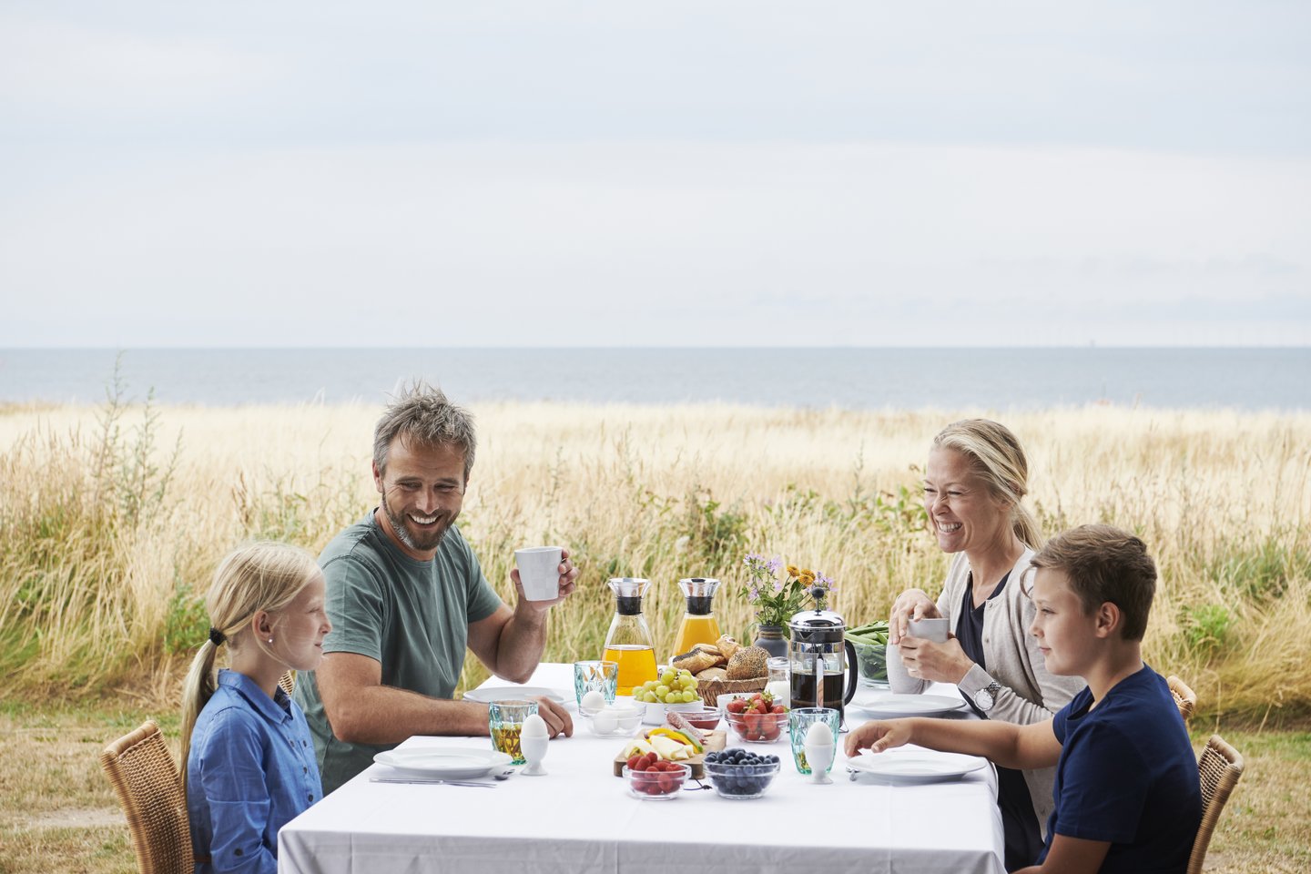 Family having breakfast outside a holiday home in Nysted, Danmark