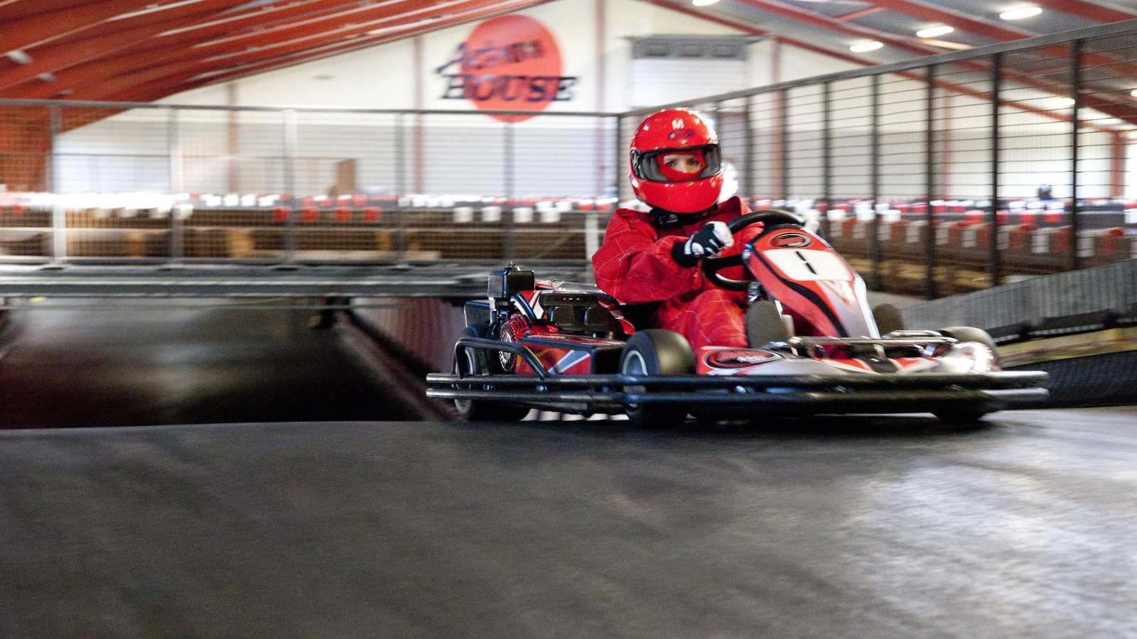Person ikledd rød kjøredrakt kjører gokart ved Action House i Løkken, Danmark