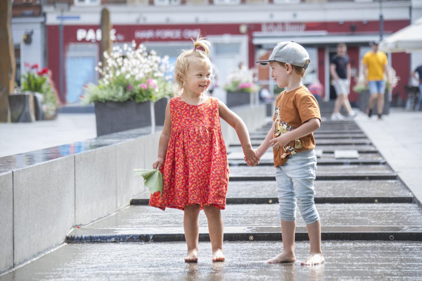 En liten jente og gutt holder hender i sentrum av Slagelse, Vestsjælland, Danmark