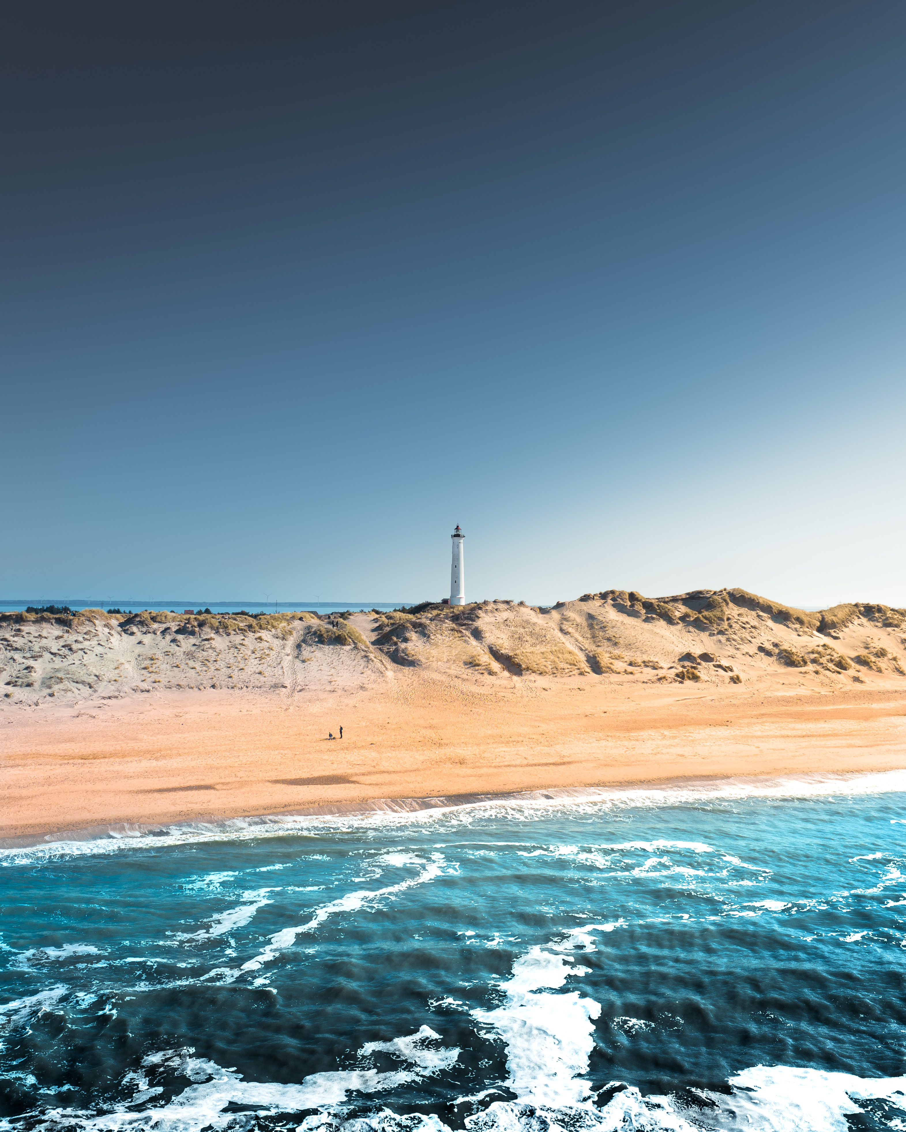 Bild vom Lyngvig Leuchtturm mit einem Strand und Wasser im Vordergrund