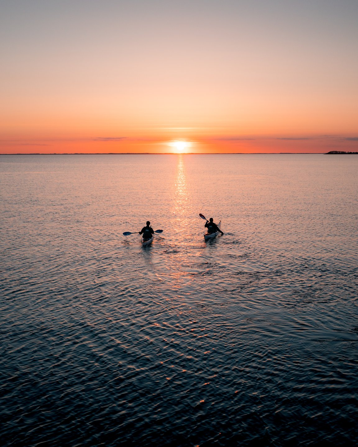 to personer kajakkpadler i solnedgangen ved Assens på Fyn, Danmark