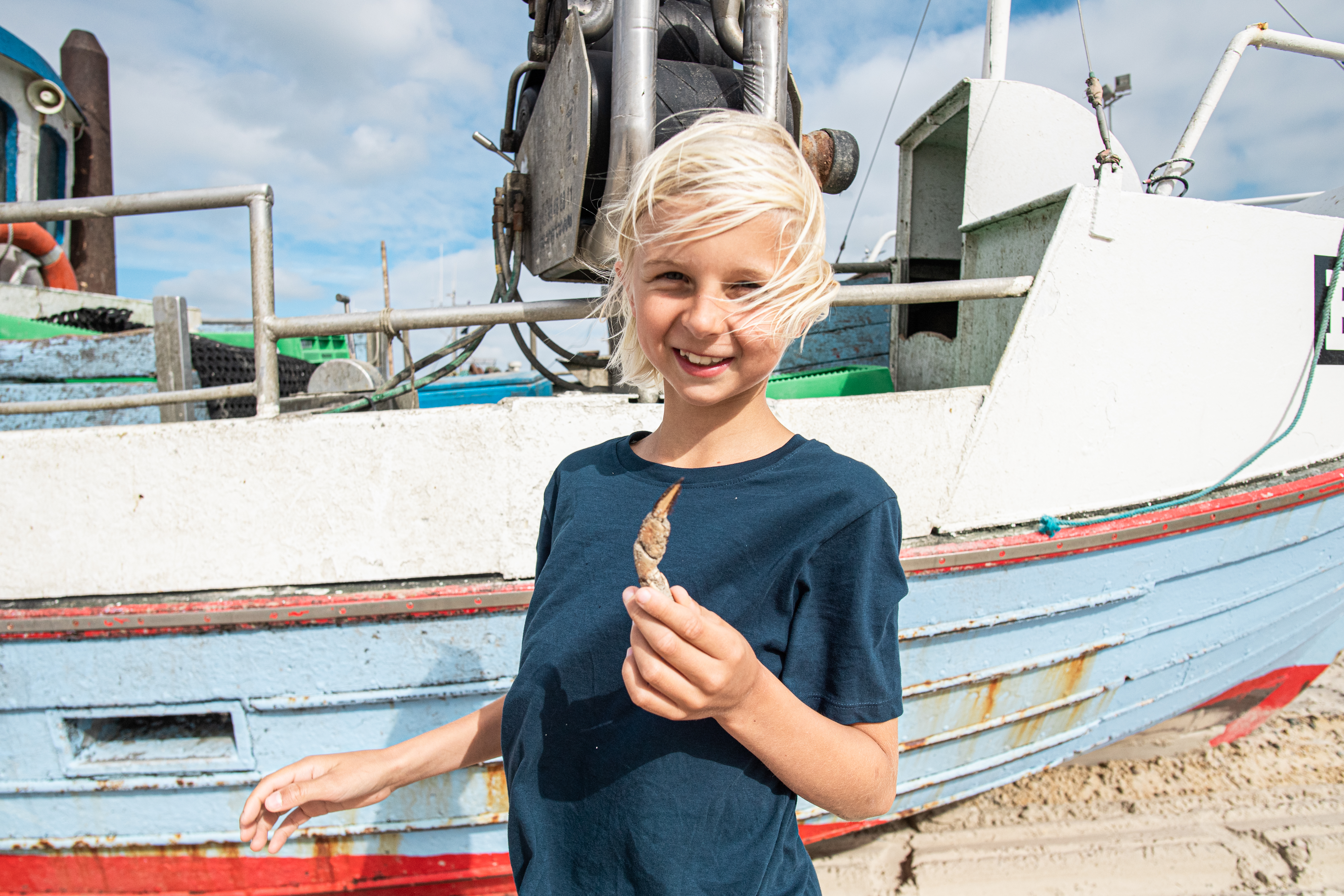 Ein Bild von einem Kind vor einem Fischerboot am Strand in Thorupstrand