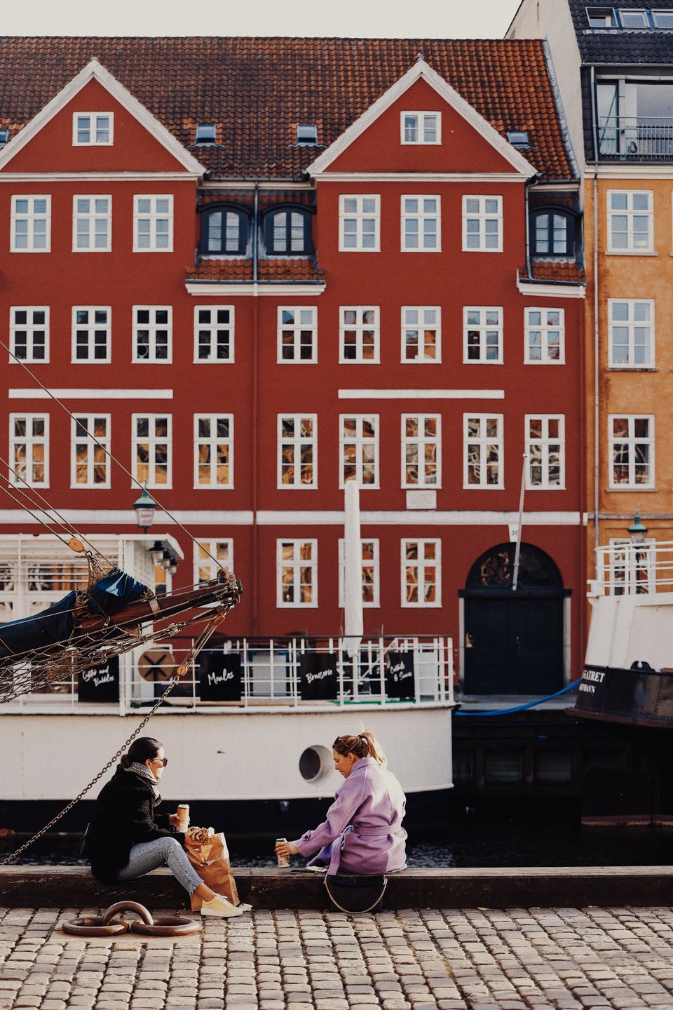 Two women sitting at Nyhavn in Copenhagen