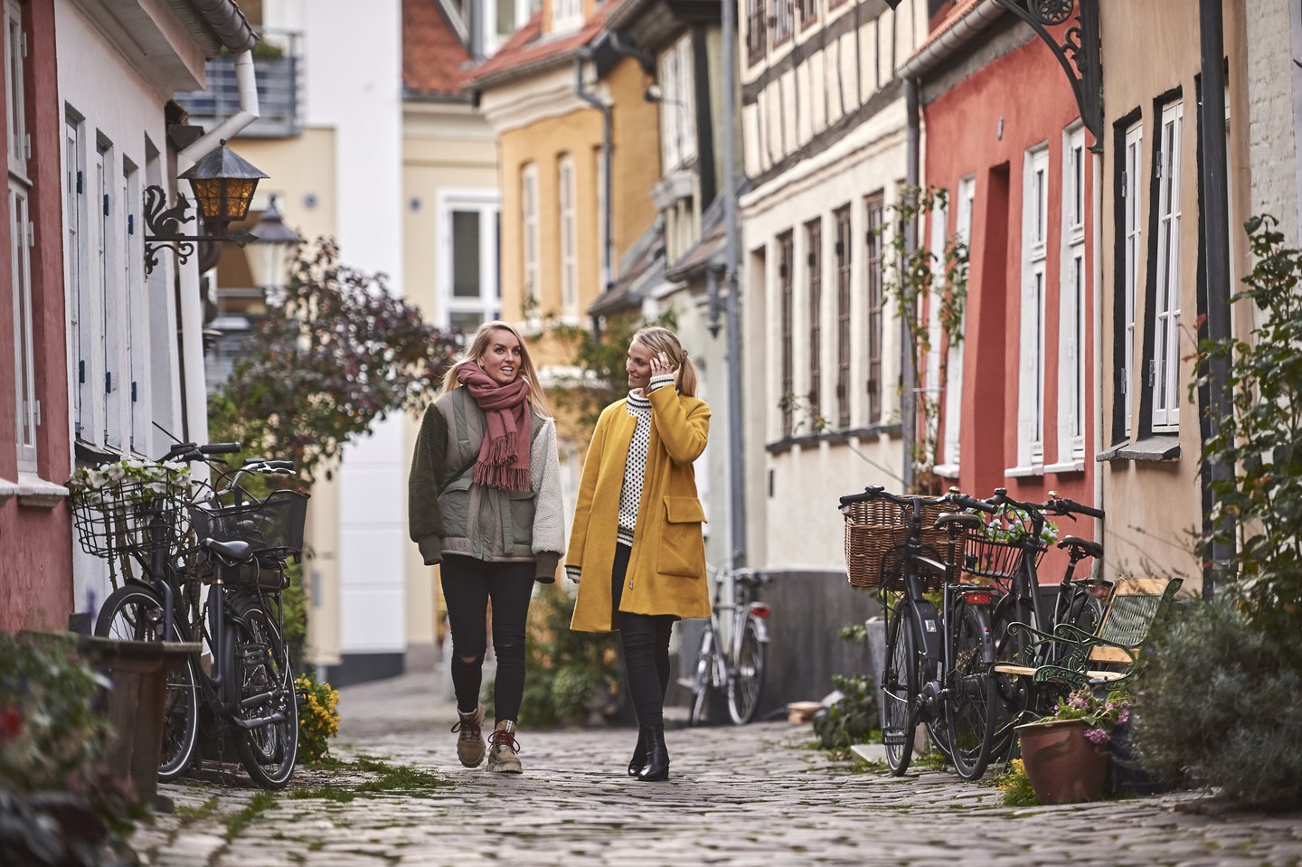 To kvinner går i Aalborgs gater på høsten