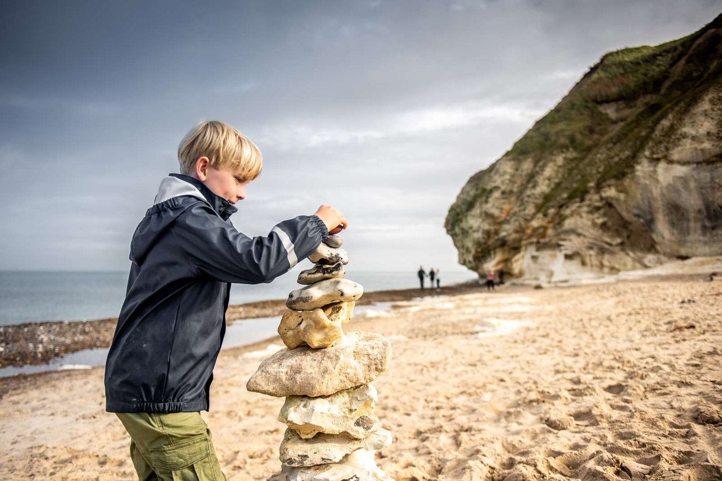 Child playing on the beach with stones in Dnemark,  Bulbjerg