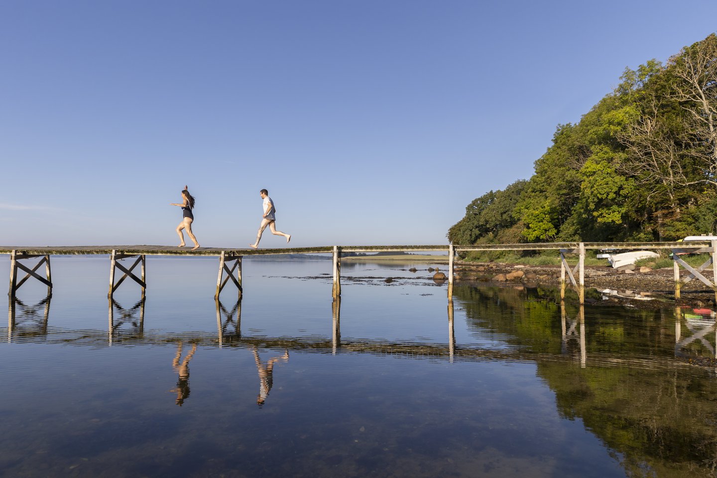 Een stel rent over de brug naar zee bij Sondrup Strand aan het Horsens Fjord