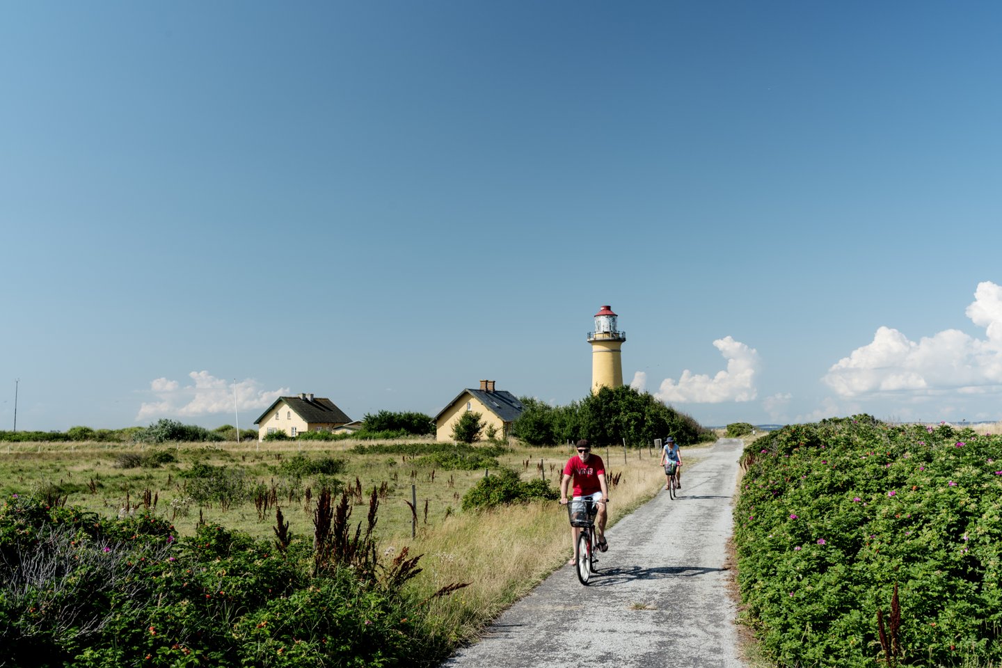 Fietsers passeren de Omø Fyr vuurtoren op het Deense eiland Omø