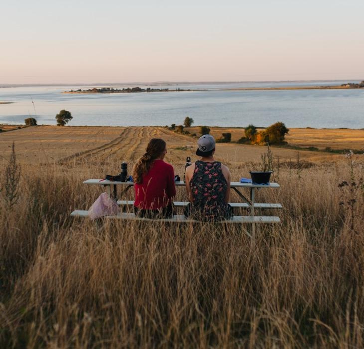 Couple looking over the water, sitting on a bench in Fyn, Denmark.