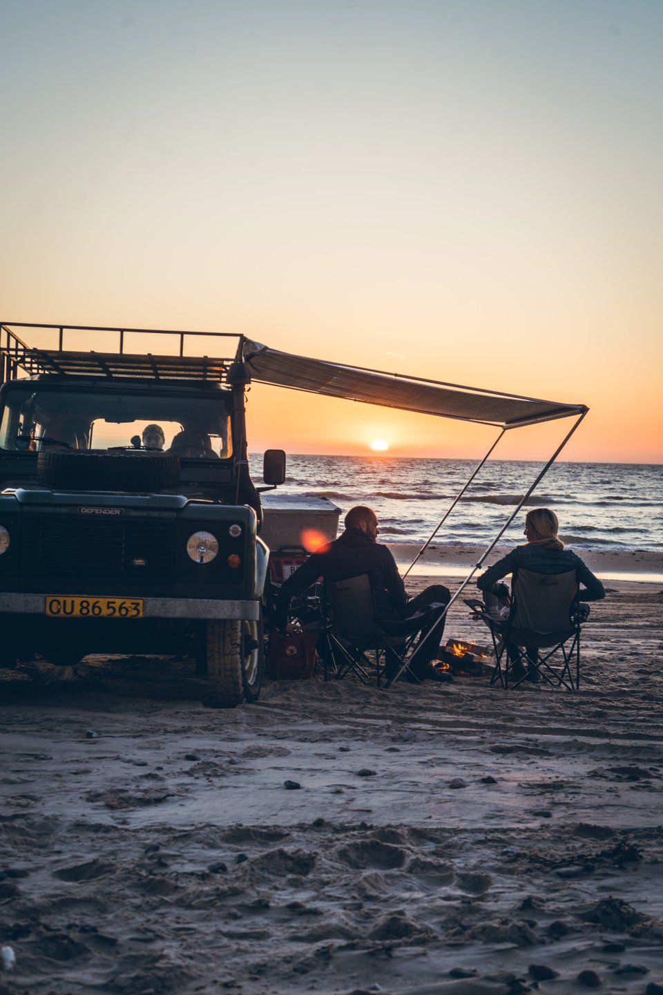 Twee kampeerders genieten van de zonsondergang op het strand bij Nørre Lyngby in Denemarken