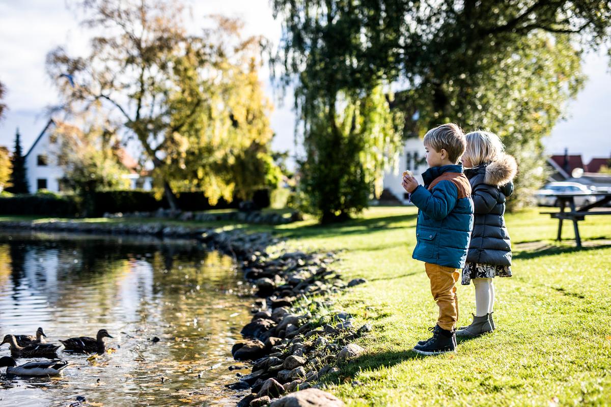Barn mater ender ved en dam i Juelsminde om høsten