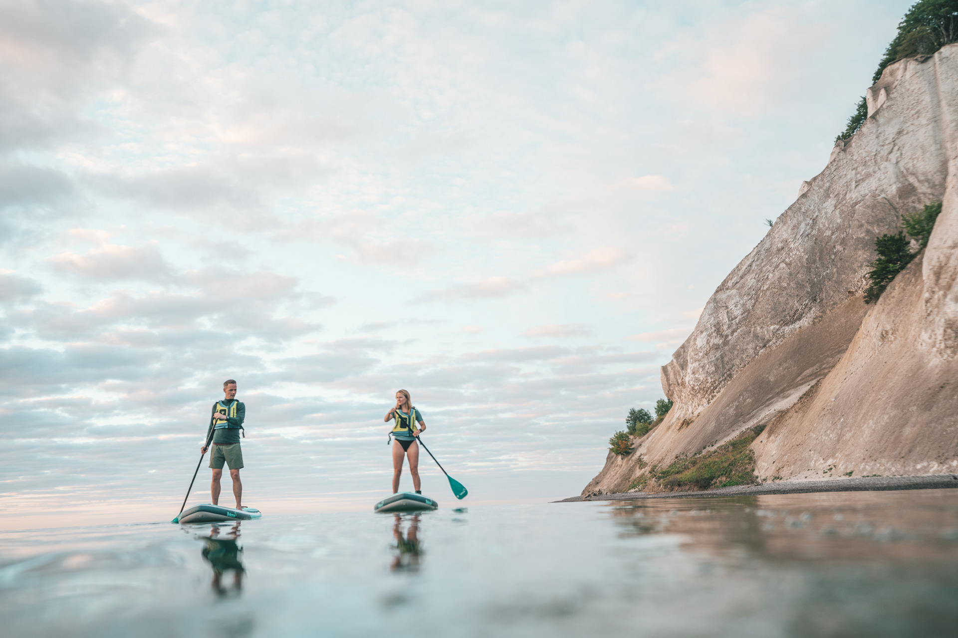 Two people paddle on a Stand up paddle board