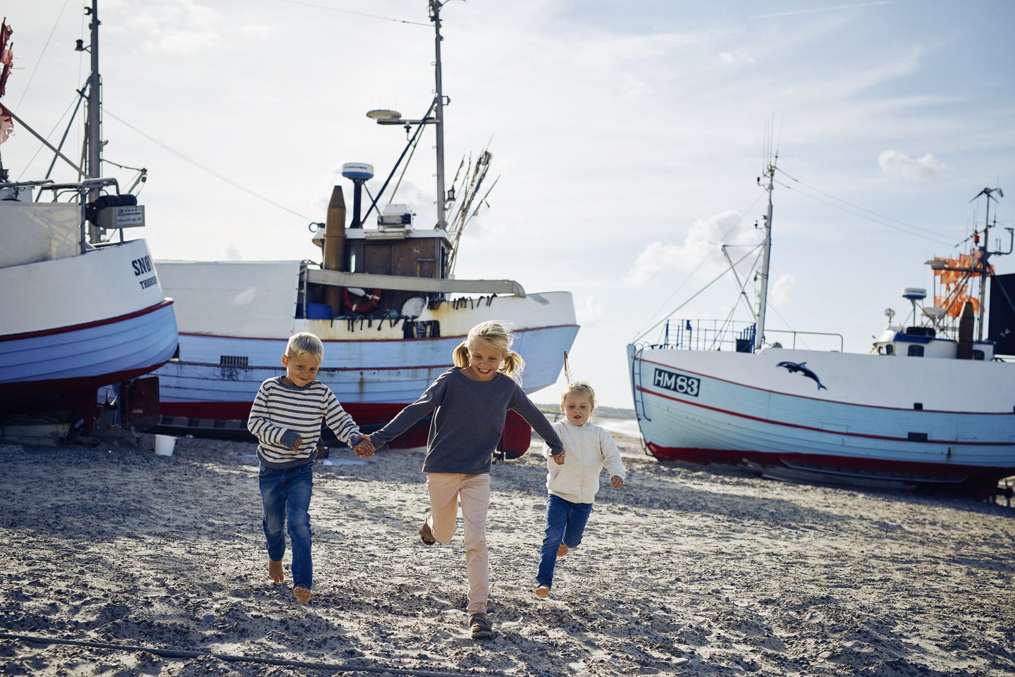 Tre barn som løper på Thorup strand i Nordjylland