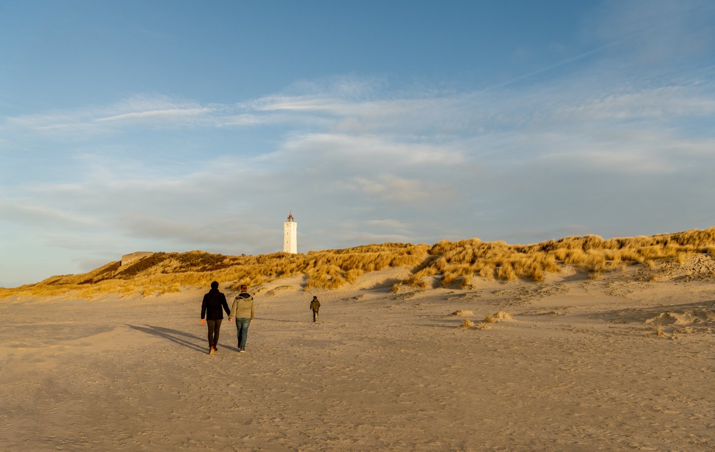 Et par med barn som går langs stranden på Blåvand i Danmark