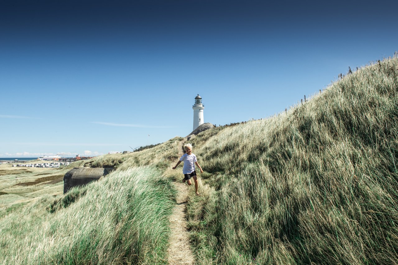 Gutt som løper i gresset ved Hirtshals fyr