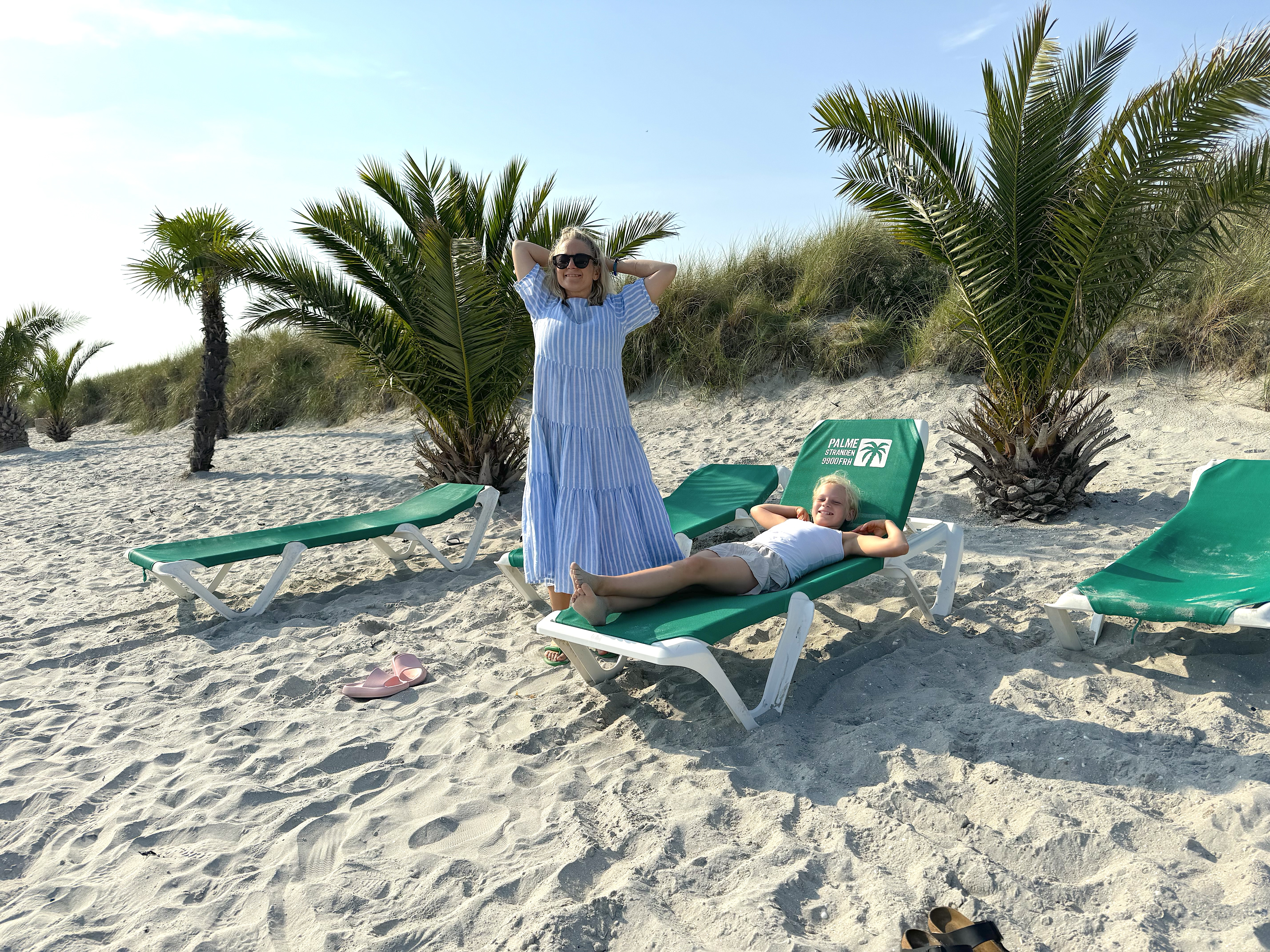Lisa står på palmstranden och hennes dotter ligger på solstol
