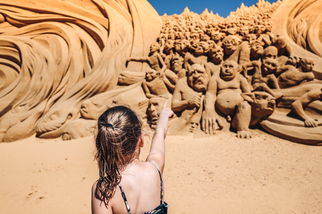 Een meisje wijst naar de reusachtige zandsculpturen van het jaarlijks terugkerende zandsculpturen festival in Søndervig, Denemarken