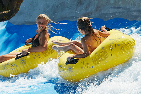 Two women on floating donuts on a water slide