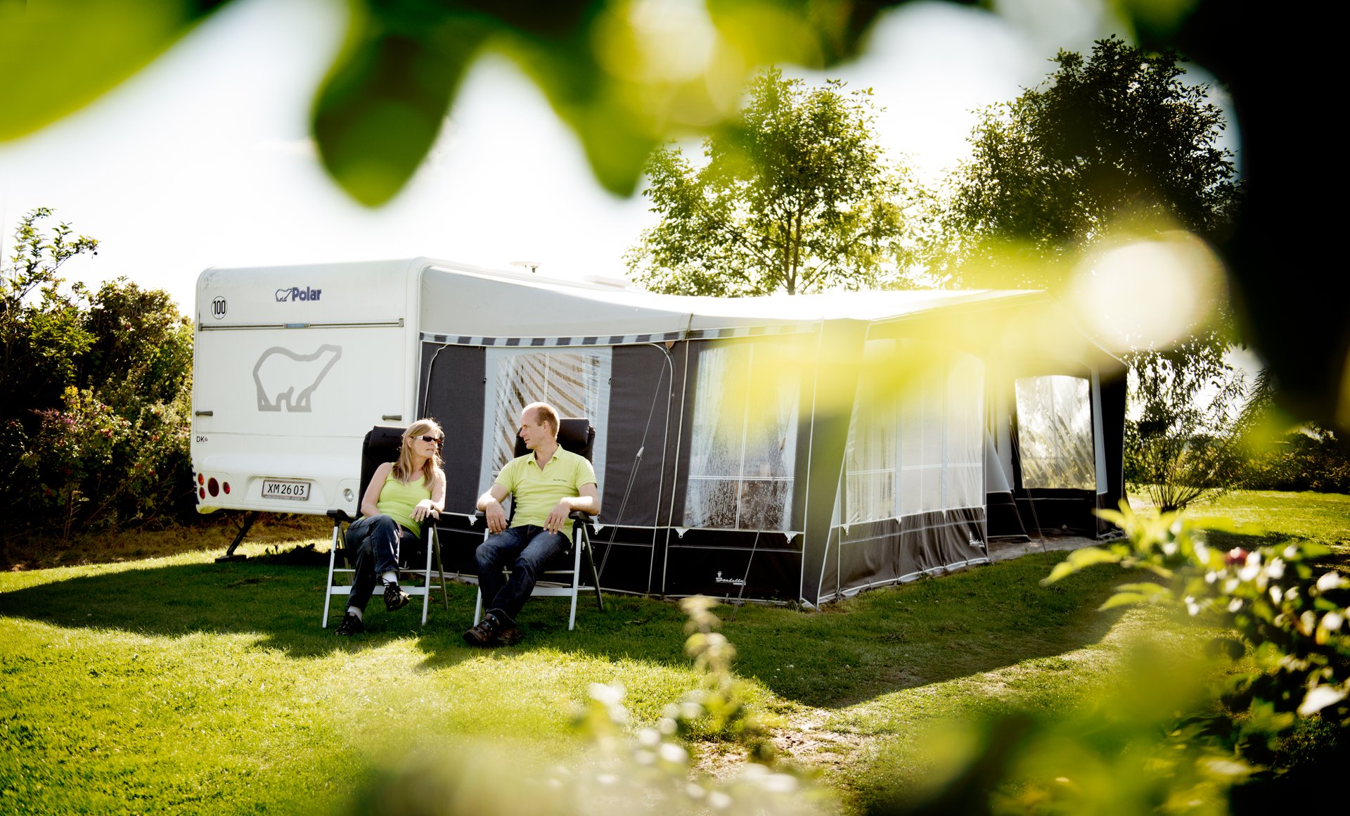 2 people sitting in front of a caravan