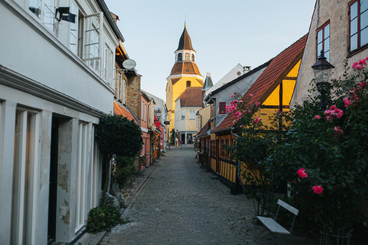 Brosteinsgate med fargerike hus, stokkroser og roser i Faaborg