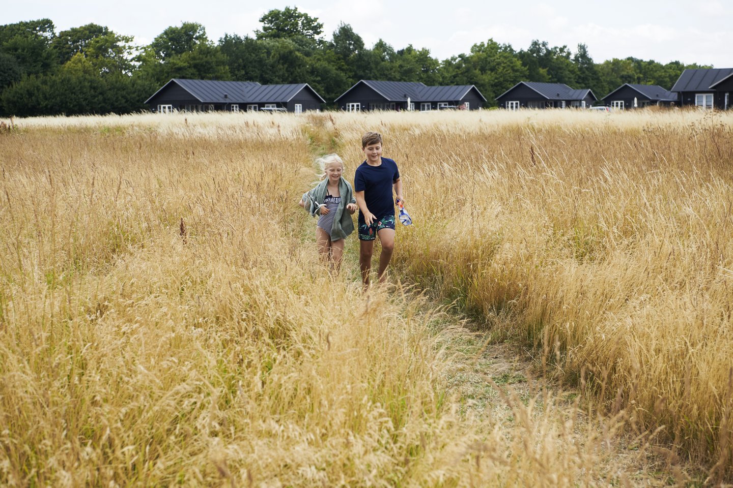 Children walking in a field close to a summer house