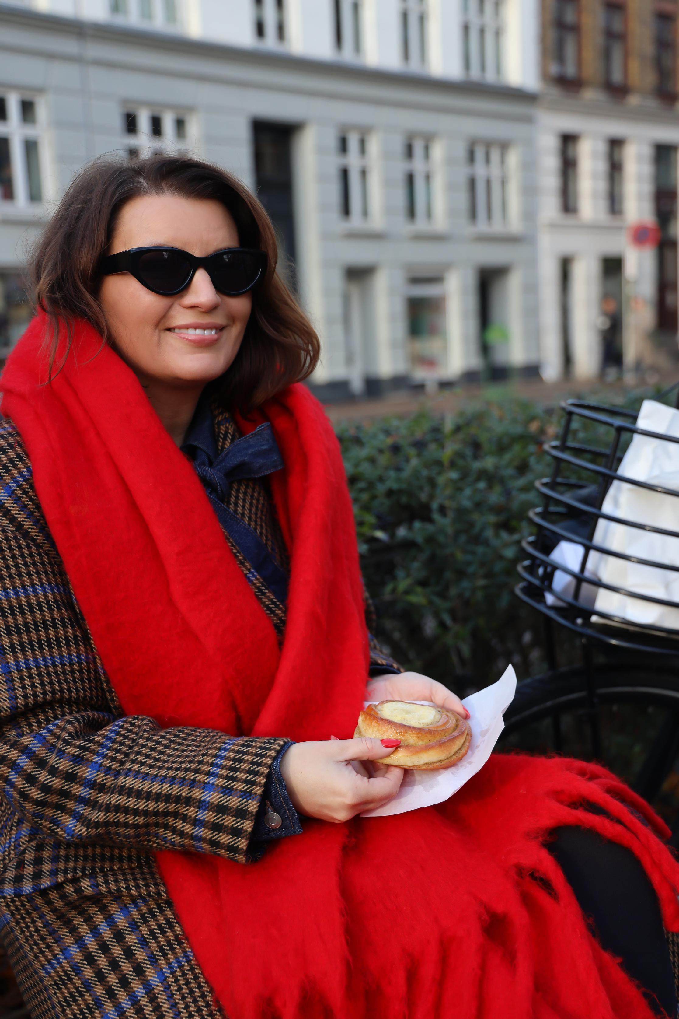 Kvinne sitter på benken og spiser bakverk