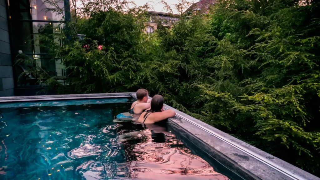 Two people in an outdoor pool at Hotel Vejlefjord