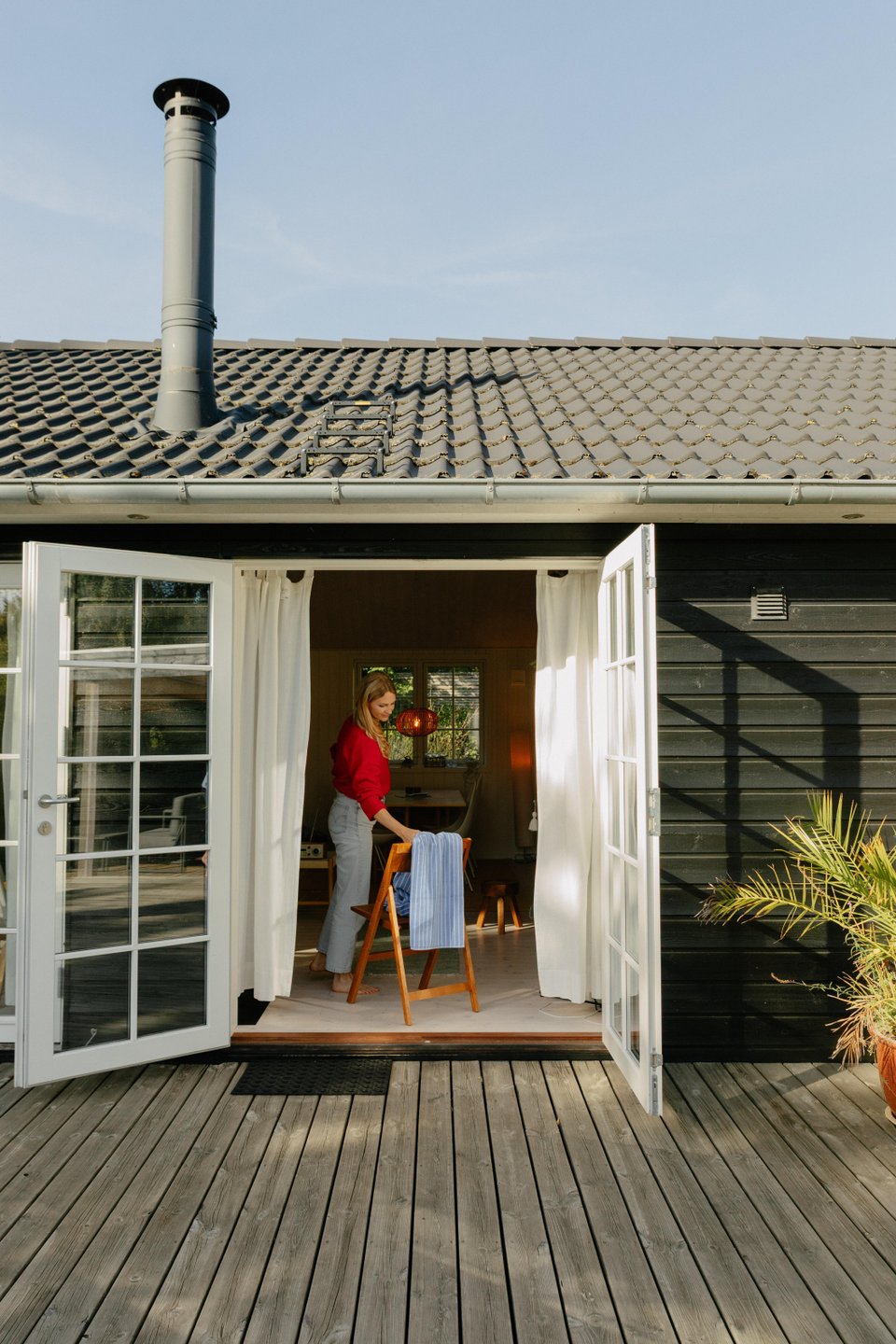 Frau nimmt Handtuch von Stuhl im Ferienhaus in Nordseeland, Dänemark