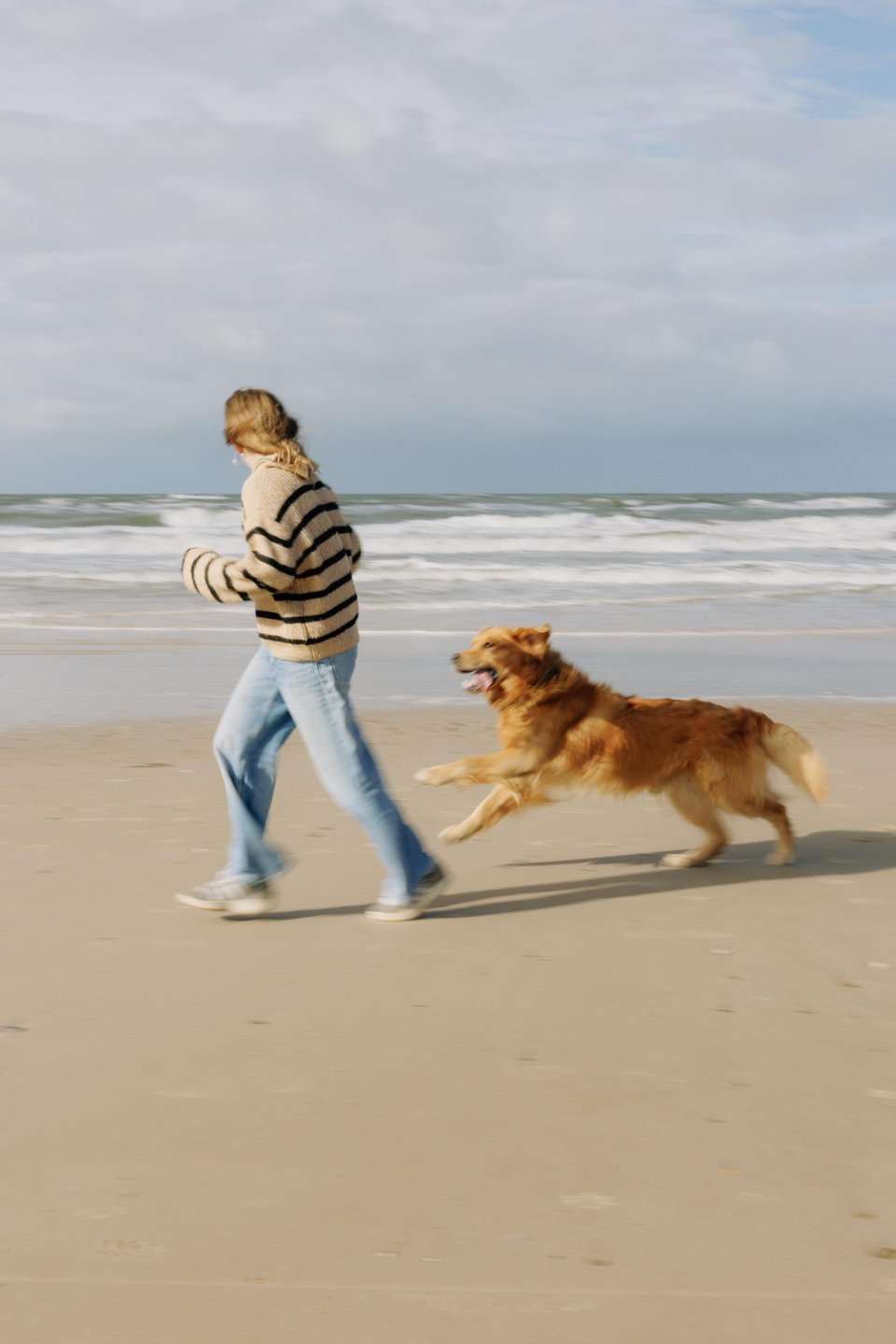 Kind läuft mit Hund am Strand der Dänischen Westküste