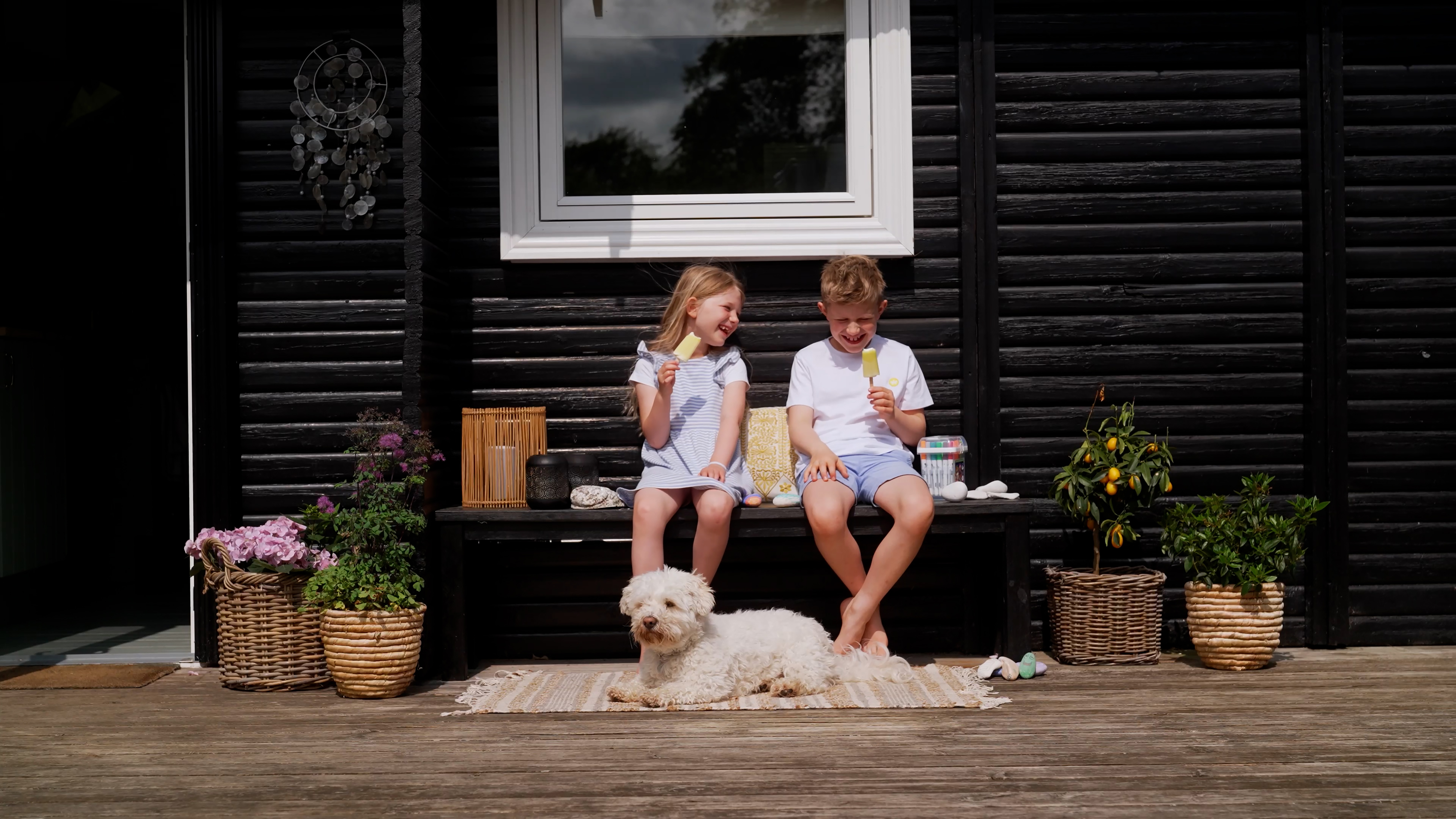 Kinder essen Eis vor einem Ferienhaus
