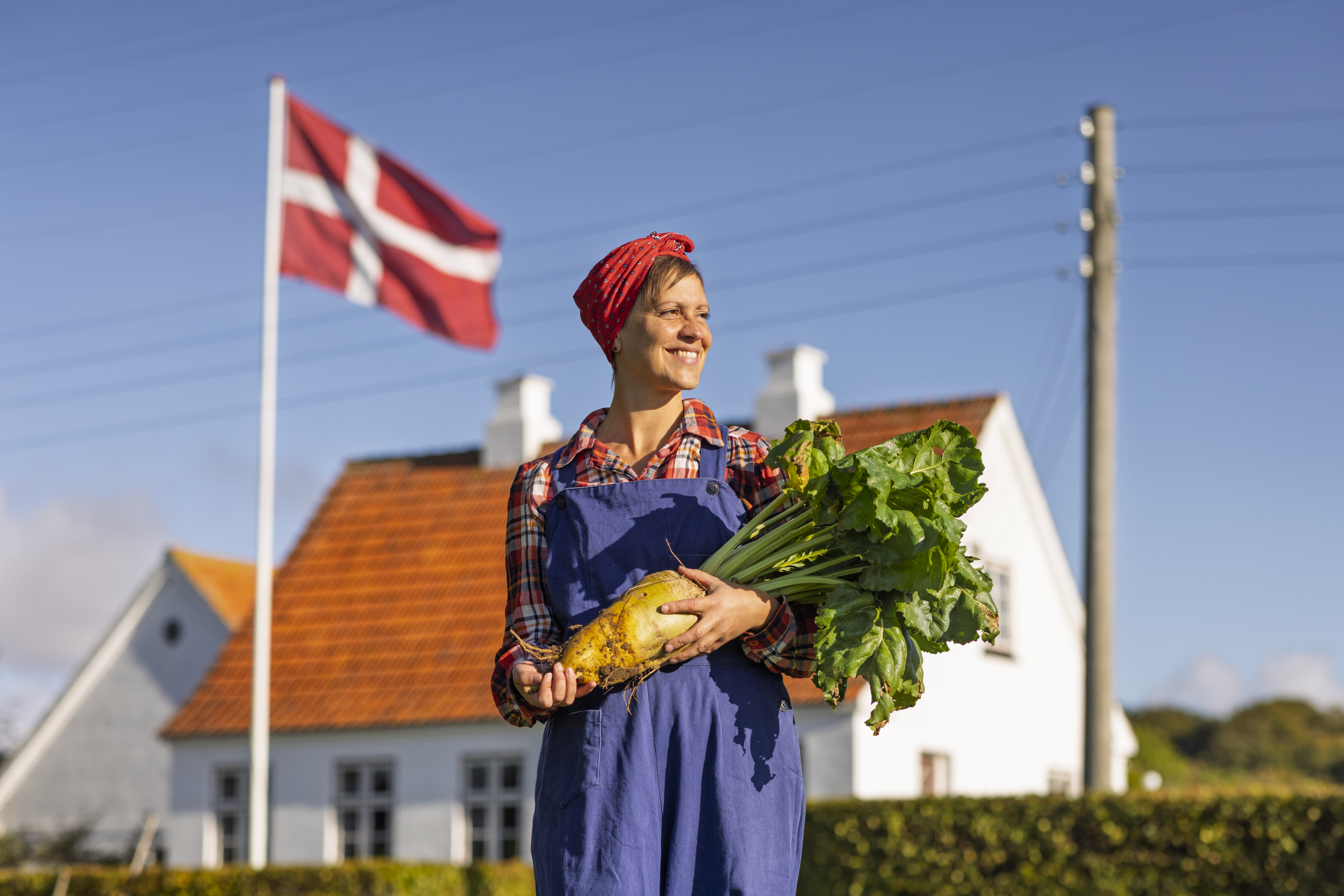 Frau vor einem Haus mit Pflanze in der Hand